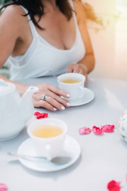 Çay bardağı ve WOMANS elleri ile masada bir fincan tutan gül yaprakları, üst görünüm.