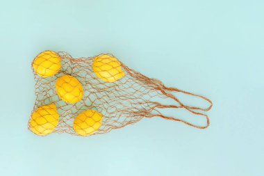 Mavi arka plan üzerinde limon ile yeniden kullanılabilir çanta. Sıfır atık ve plastiksiz alışveriş konsepti.