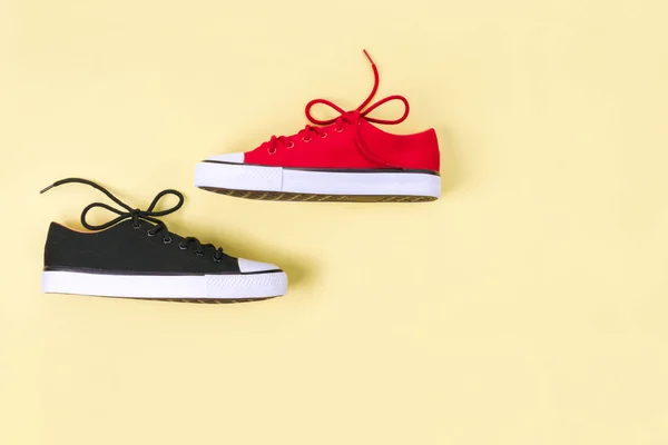 Nya röda och svarta sneakers på gul bakgrund med kopierings utrymme. — Stockfoto