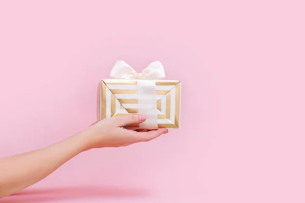 Frauenhände mit Geschenk- oder Geschenkbox auf rosa Pastellhintergrund. — Stockfoto