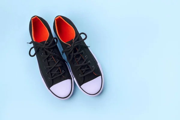 Mavi arkaplanda fotokopi alanı olan yeni siyah spor ayakkabılar. — Stok fotoğraf