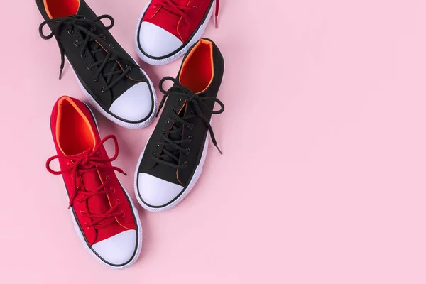 Nya röda och svarta sneakers på rosa bakgrund med kopieringsutrymme. — Stockfoto