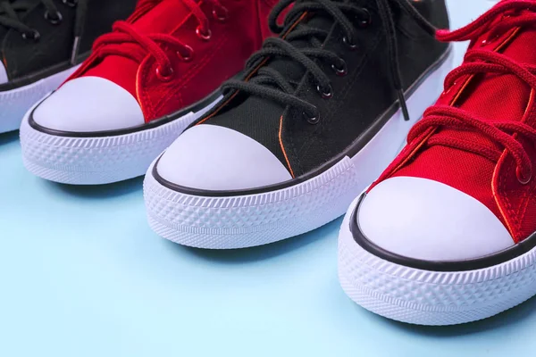 Nya svarta och röda sneakers på ljusblå bakgrund med kopierings utrymme. — Stockfoto