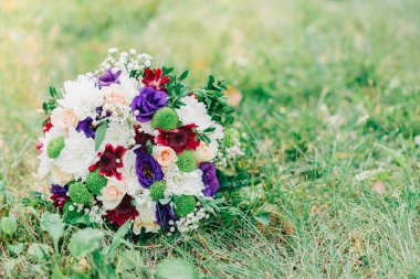 Yumuşak bir demet menekşe, pembe ve beyaz çiçekler yeşil çimenlerin üzerinde yatıyor..