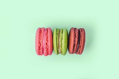 Nane yeşili arkaplanda kopyalama alanı olan çeşitli renkli badem kurabiyeleri.