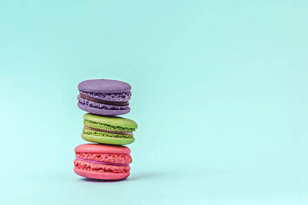 Assorted colorful macaroons on mint green background with copy space.