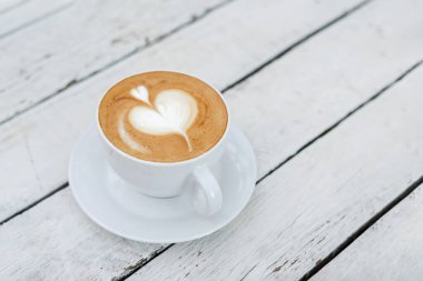 Beyaz ahşap masa üzerinde fotokopi alanı olan büyük beyaz kahve fincanı..