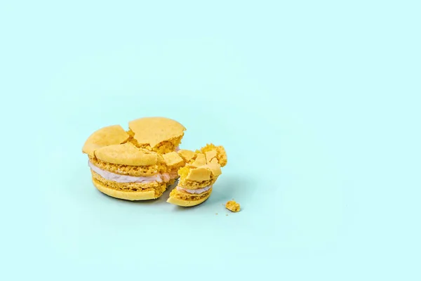 Macarrón amarillo aplastado sobre fondo azul pastel con espacio para copiar . — Foto de Stock