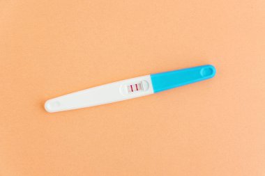Turuncu arka planda pozitif hamilelik testi. Hamilelik planlaması, bebek sahibi olmaya çalışmak..