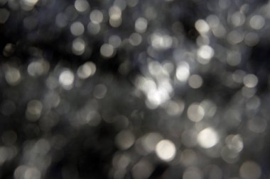 Hassas beyaz parıltılı bokeh ile soyut odaklanmış siyah arkaplan. Bulanık.