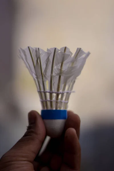 White Shuttlecock em uma mão. Atividade ao ar livre, no estilo de vida à noite. Fundo do equipamento de exercício — Fotografia de Stock