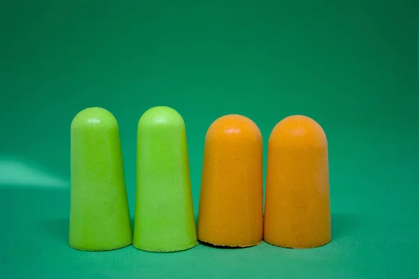 Bouchons d'oreilles multicolores sur fond vert. Gros plan. Concentration sélective — Photo