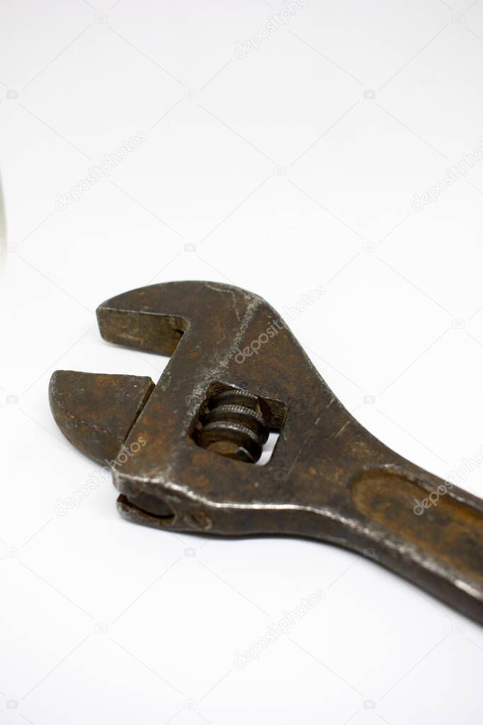 Old, rusty adjustable wrench on a white background close-up.