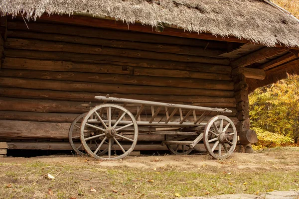 Carrinho de madeira velho na frente de um celeiro velho. Paisagem rural — Fotografia de Stock