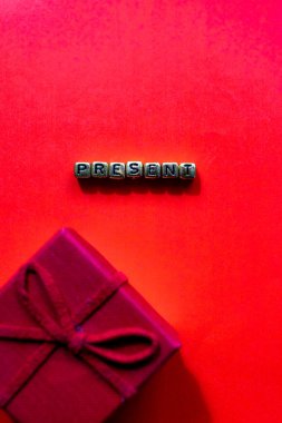 Şimdiki konsept. Kırmızı arka planda yeni yıl hediyeleri. Kırmızı arkaplanda Noel kompozisyonu ve altın harflerle yazılmış yazı. Metin için en üstteki görünüm. Düz yatıyordu