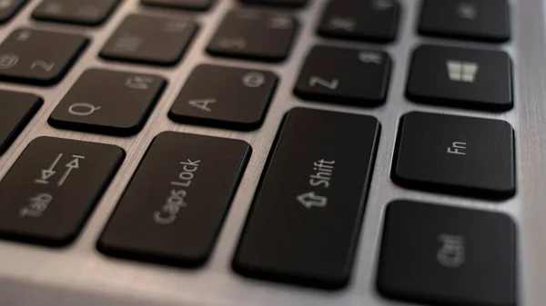 Laptop computer keyboard close up. Black English Russian letters on a metal background. — Stock Photo, Image