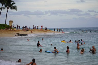 Akşamüstü Kauai 'deki Poipu Plajı' nda oynayan aileler