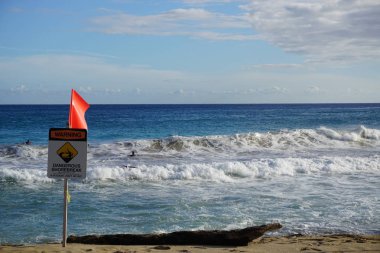 Kauai 'deki Poipu Sahili' nde tehlikeli kıyı tabelası uyarısı. Kıyı tatili sörfçüler için ideal Pasifik Okyanusu dalgaları yaratır..