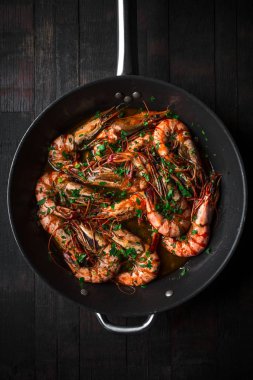 Karides bir tencerede kızartılır. Klasik tarifin - maydanoz, sarımsak, kırmızı biber ve beyaz şarap.