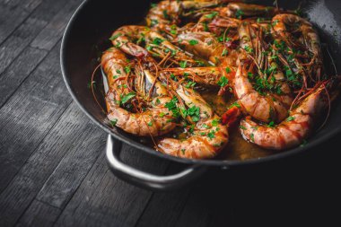 Karides bir tencerede kızartılır. Klasik tarifin - maydanoz, sarımsak, kırmızı biber ve beyaz şarap.