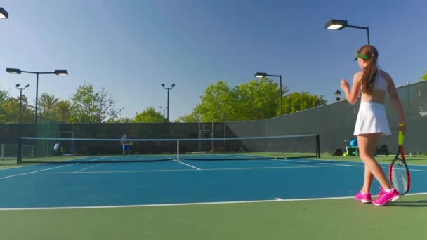 Visão de fundo em câmera lenta de uma atleta servindo uma bola de tênis em um campo — Vídeo de Stock