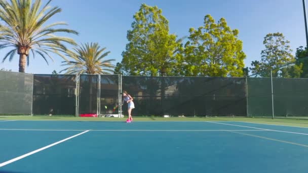 Langzame beweging van een jonge atleet die op een tennisbaan rent en de bal slaat — Stockvideo