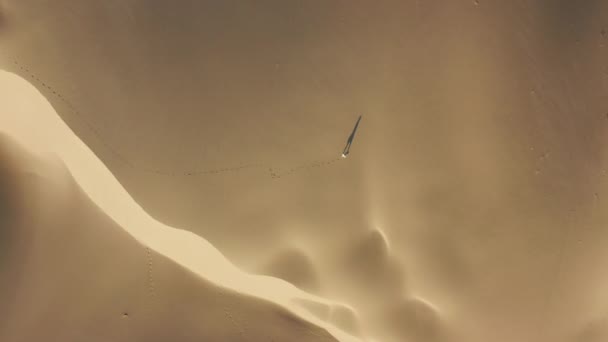 4K vue aérienne d'un modèle féminin marchant par les dunes de sable dans la nature désertique — Video