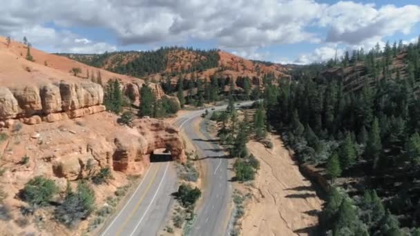 Bryce kanyon. 4K antenna a Bryce Canyon felé vezető út feletti természetes sziklaíven — Stock videók