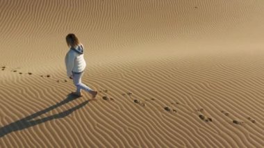 4K yavaş çekim hava görüntüsü. Kum tepesi üzerinde yürüyen kadın, ABD doğası.