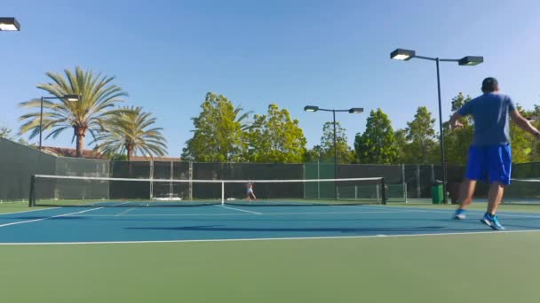 Il rallentatore dalla vista posteriore di un maschio maturo che gioca attivamente a tennis su un campo — Video Stock