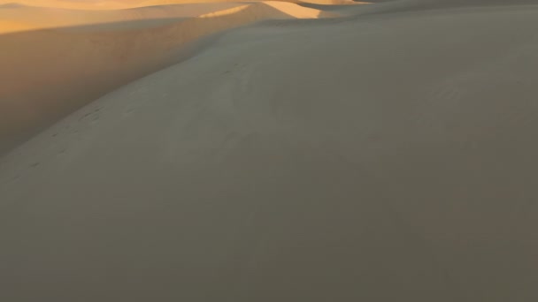 황금 석양 빛 가운데 마법같은 모래 언덕을 지나는 4K 공중 드론 — 비디오
