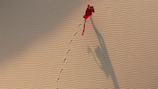 4K slow motion overhead aerial of a woman walking by sand dunes to sunset light — Stock Video