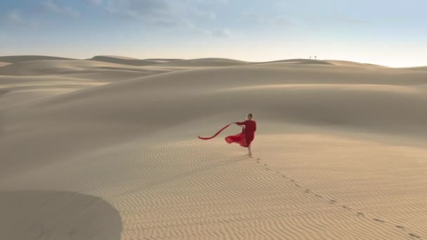 4K vue aérienne du modèle dans une robe rouge à la mode marchant dans la nature déserte