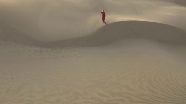 Mujer caminando por la naturaleza salvaje del desierto. Vista aérea en cámara lenta 4K de dunas de arena — Vídeos de Stock