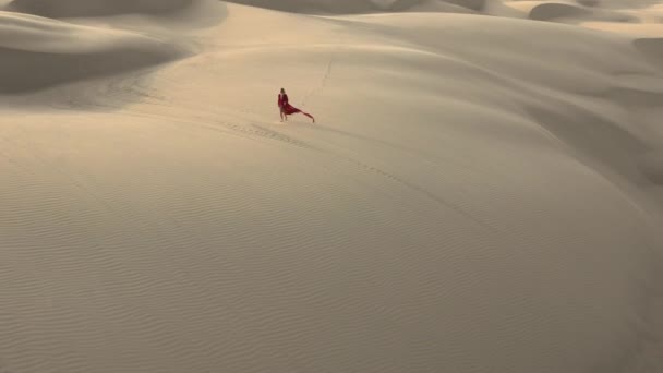 4K insansız hava aracı, çöl doğasında kumulların arasında yürüyen bir kadının uzaktan görüntüsü. — Stok video