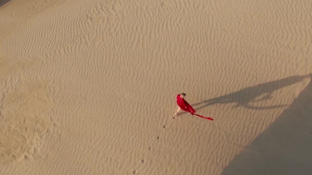 4K εναέρια άποψη της γυναίκας με τα πόδια από την κορυφή της άμμου αμμόλοφος στο ηλιοβασίλεμα — Αρχείο Βίντεο