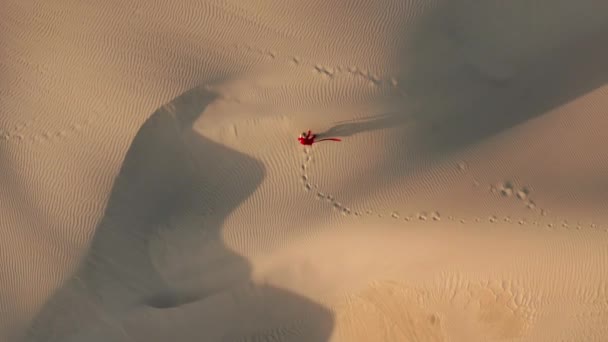 Menschen erschossen. 4K-Luftaufnahme der Frau, die durch Dünen in der Wüstennatur wandert — Stockvideo