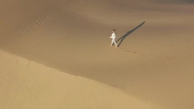 4K yavaş çekim hava görüntüsü. Kum tepesi üzerinde yürüyen kadın, ABD doğası.