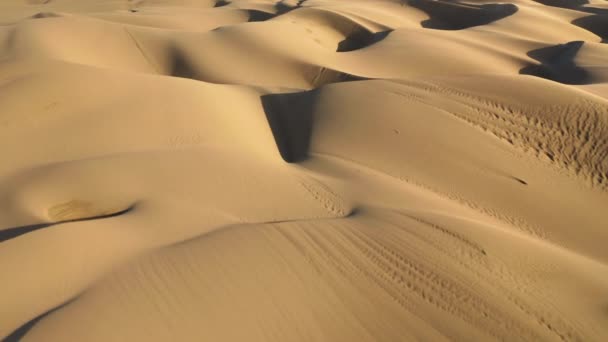 Drone 4K volando sobre dunas de arena con luz dorada al atardecer. Fondo abstracto — Vídeos de Stock