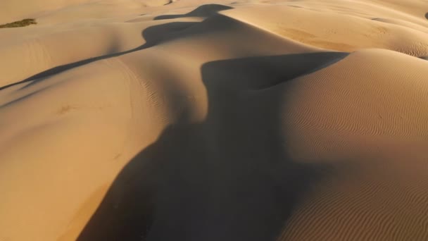 4K antena de areia empoeirada dourada soprada pelo vento ao pôr-do-sol no deserto — Vídeo de Stock