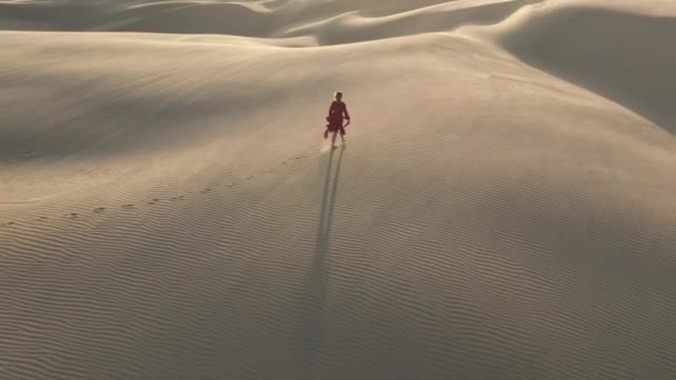 Natureza selvagem viagens 4K vídeo aéreo. Mulher está andando pela duna de areia ao pôr do sol — Vídeo de Stock