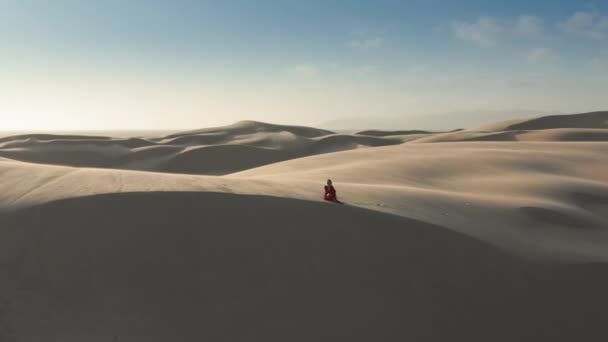 4K aérea de la mujer en un vestido rojo en medio de dunas de arena y desierto — Vídeos de Stock