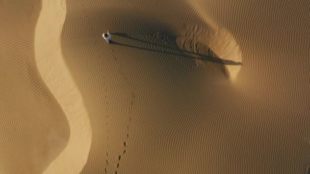 4K-Luftaufnahme der Frau, die durch Sanddünen in der Wüstennatur geht — Stockvideo