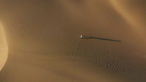 4K-Luftaufnahme der Frau, die durch Sanddünen in der Wüstennatur geht — Stockvideo