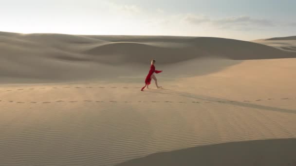 4K vue aérienne d'une fille marchant au sommet des dunes de sable dans la nature désertique