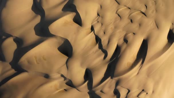 4K повітряний безпілотник збільшує масивні хвилясті піщані дюни в золотому світлі заходу сонця — стокове відео