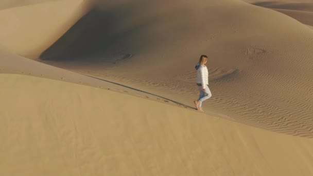 4K slow motion vue aérienne de la femme marchant au sommet d'une dune de sable, USA nature