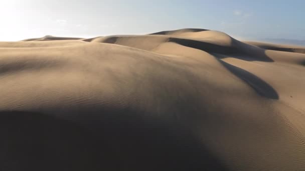 4K antena no vento soprando a areia do topo de dunas de areia dourada ondulada — Vídeo de Stock