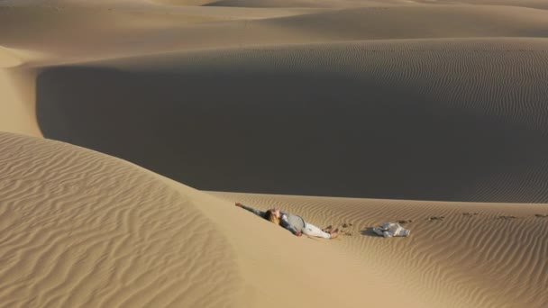 Kum tepesinde rahatlayan kadının 4K yavaş çekim hava görüntüsü, ABD doğası. — Stok video