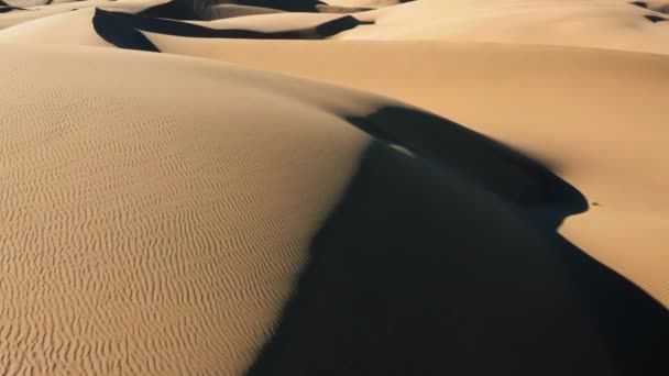 Vista aérea del dron 4K volando por hermosas dunas de arena ondulada en luz dorada del atardecer — Vídeo de stock